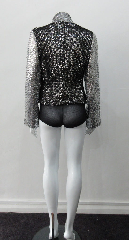 Silver Glitter Jacket with Black Crochet. Full on glittered siver colour sequin jacket with partblack crochet covered for a sporty feel. Crochet detailing unravelling/fraying in areas as done for intentional effect. CF zipper with 8.5cm high collar.  CB length 52cm. Sleeve length from side neck point 76cm. 950g approximate weight. 90% Polyester, 5% Elastine, 5% Metallic Contrast: 100% Cotton. Lining: 100% Polyester. Dry Clean Only. Made in England