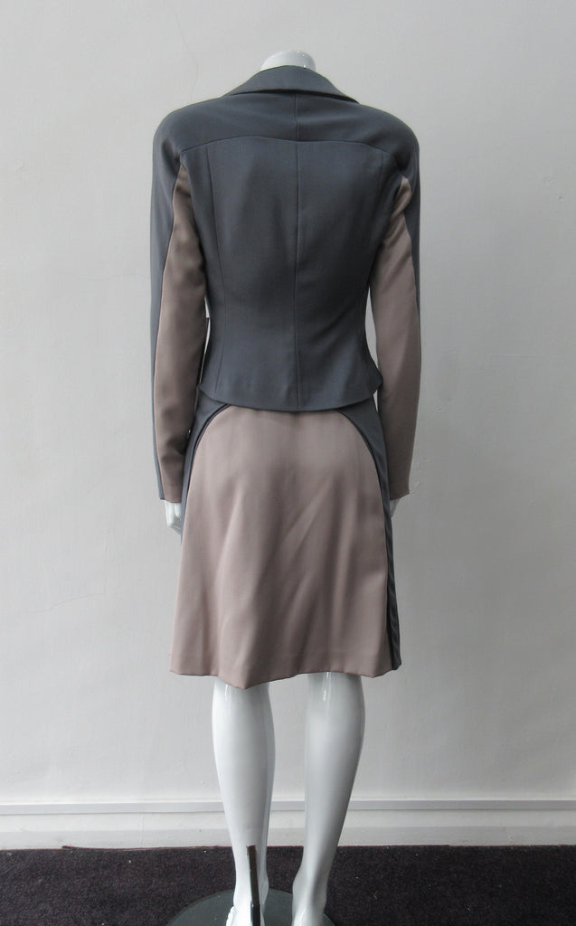 Cropped Point Sleeve Jacket. Pointed peak collared cropped style in grey with light taupe/rose contrast sleeve panels. Relaxed fit with soft raglan sleeves. Shown with matching skirt. Size 8. 100% Wool. Lining: 100% Rayon, Dry Clean Only. Made in England
