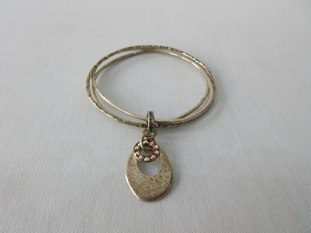 Karyn Chopik Multi 3 Ring Bracelet with Hollow Teardrop and Crystal Ring, 3 Sterling Silver Rings, 1 textured with Brass Ring attachment Size: Medium x1 6.5cm Inside diameter. 35 grams approximate weight. Made in Canada