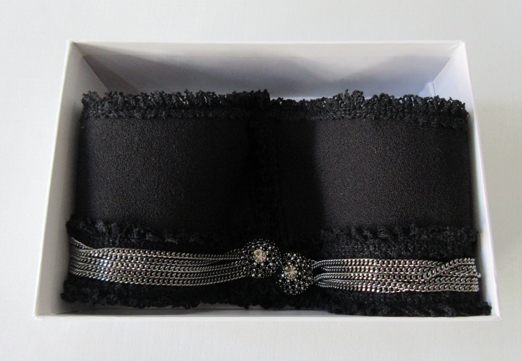 Catherine Osti Black Crepe & Chains Cuffs. Black Wool Crepe with Metal Chains and Shiny Accent Button. Snap Clousre. 19.5cm width between snaps. 60g approximate weight, comes in white box. Made in France