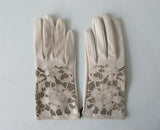 Beige Floral Cutout Gloves. Item Number D540NSF ICING 5358.0574. Beige Leather Gloves with floral cut-out design on top hand. Made in Italy. 60g approximate weight.